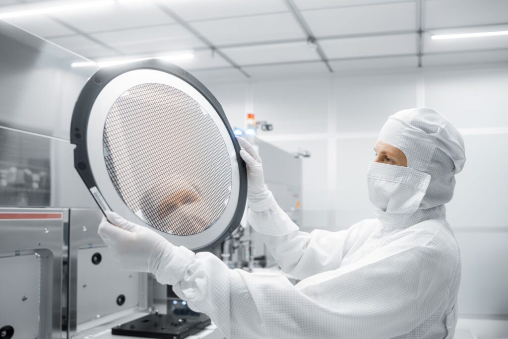 A technical engineer in the cleanroom at Infineon Technologies in Villach, Austria, holds a 300mm gallium nitride wafer.